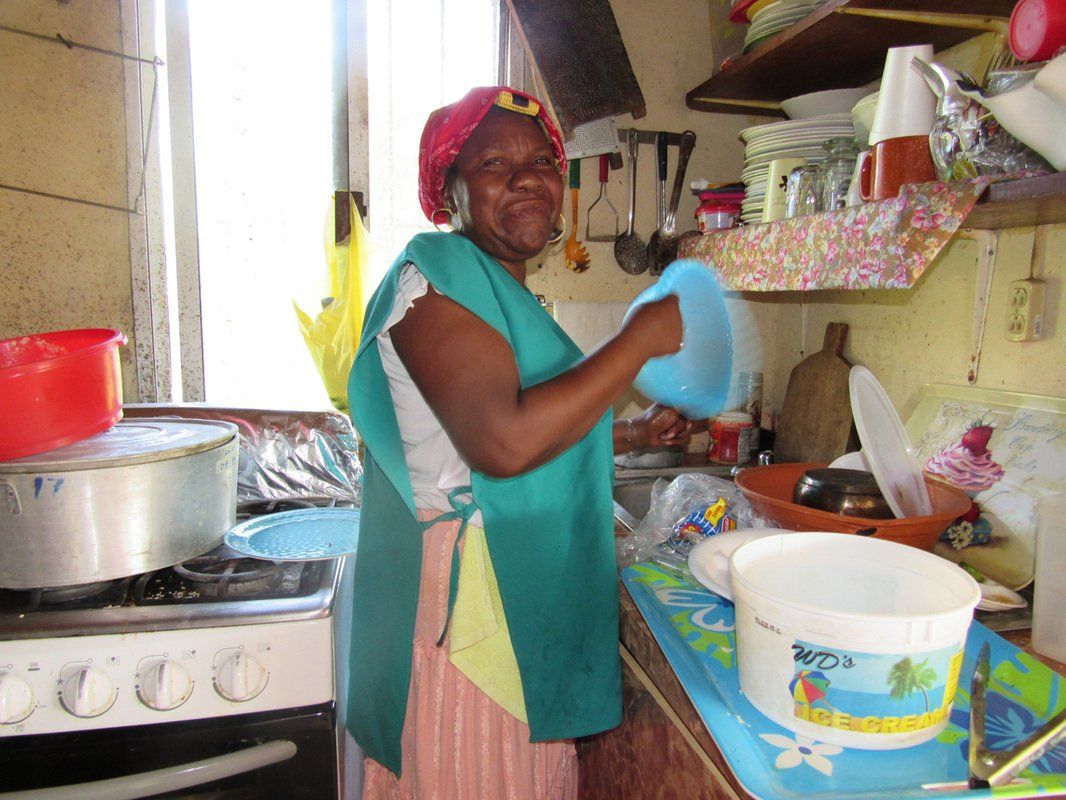 A woman is standing in a kitchen washing dishes