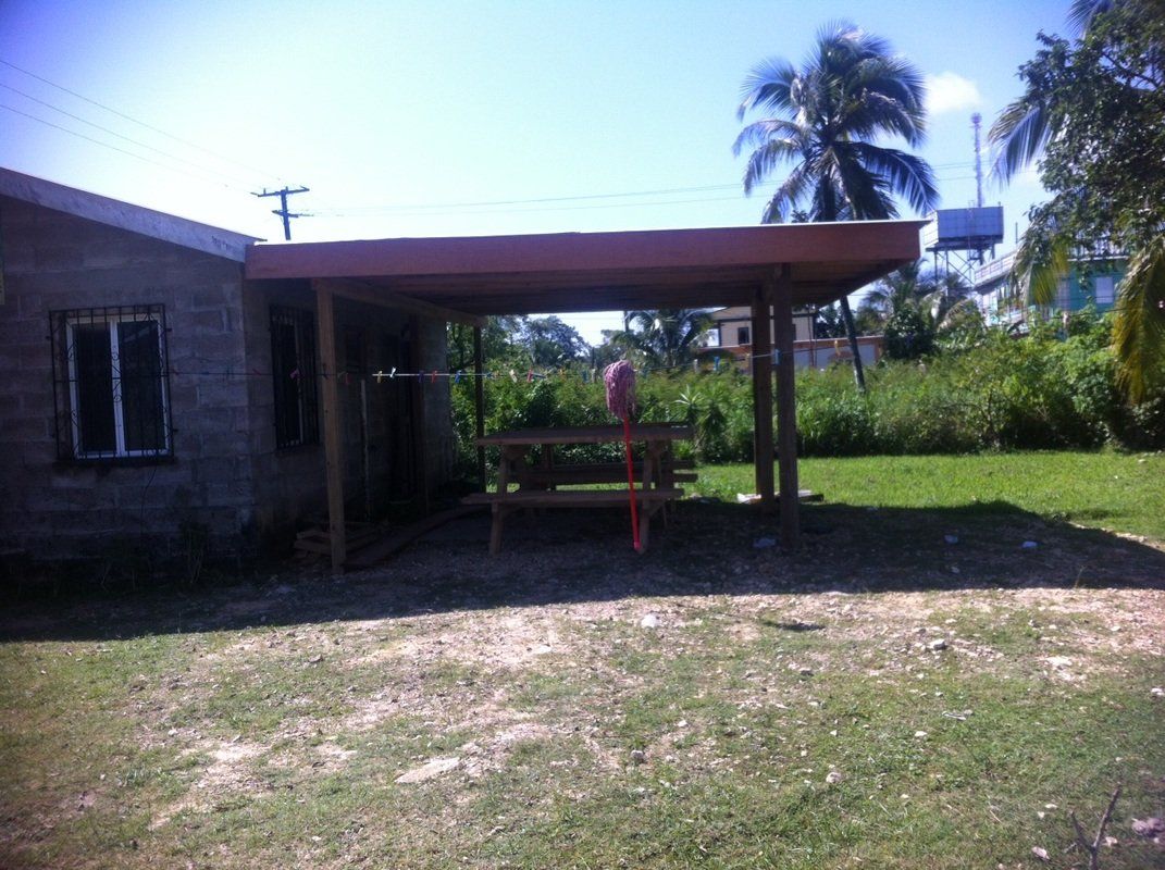A house with a carport and a picnic table in front of it.