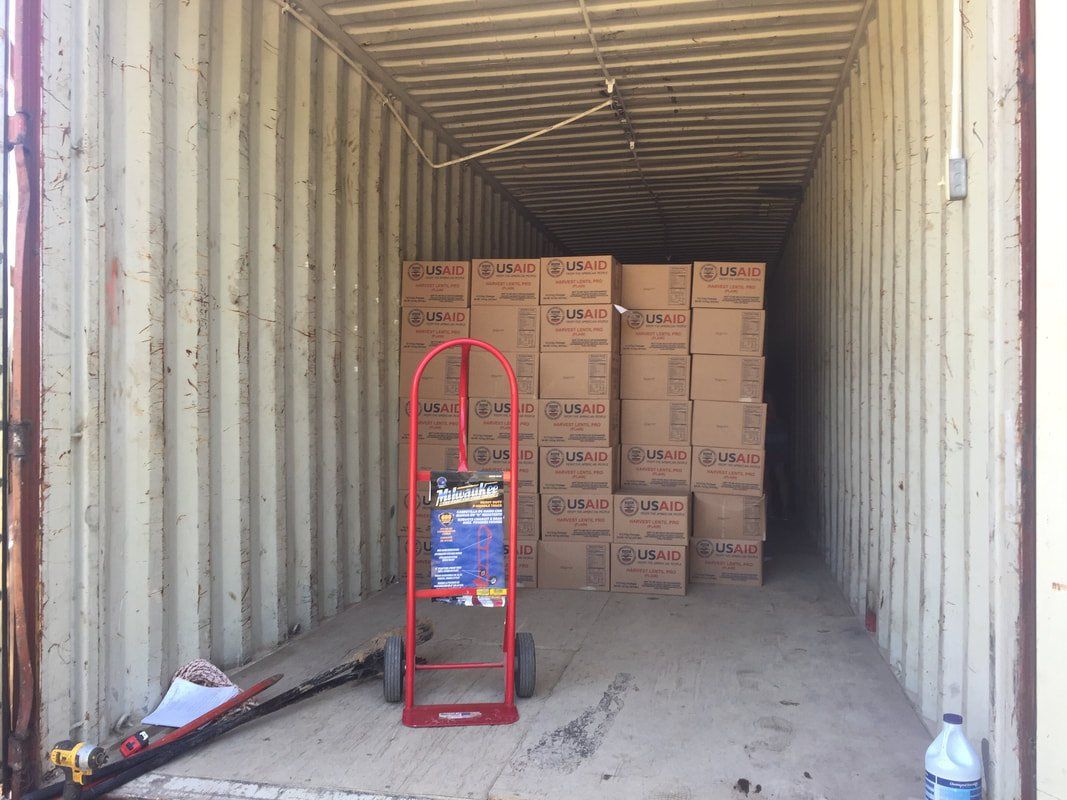 A shipping container filled with boxes and a hand truck.