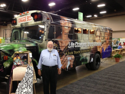 A man stands in front of a bus that says life changer