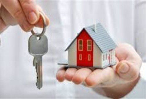 A person is holding a model house and keys in their hands.