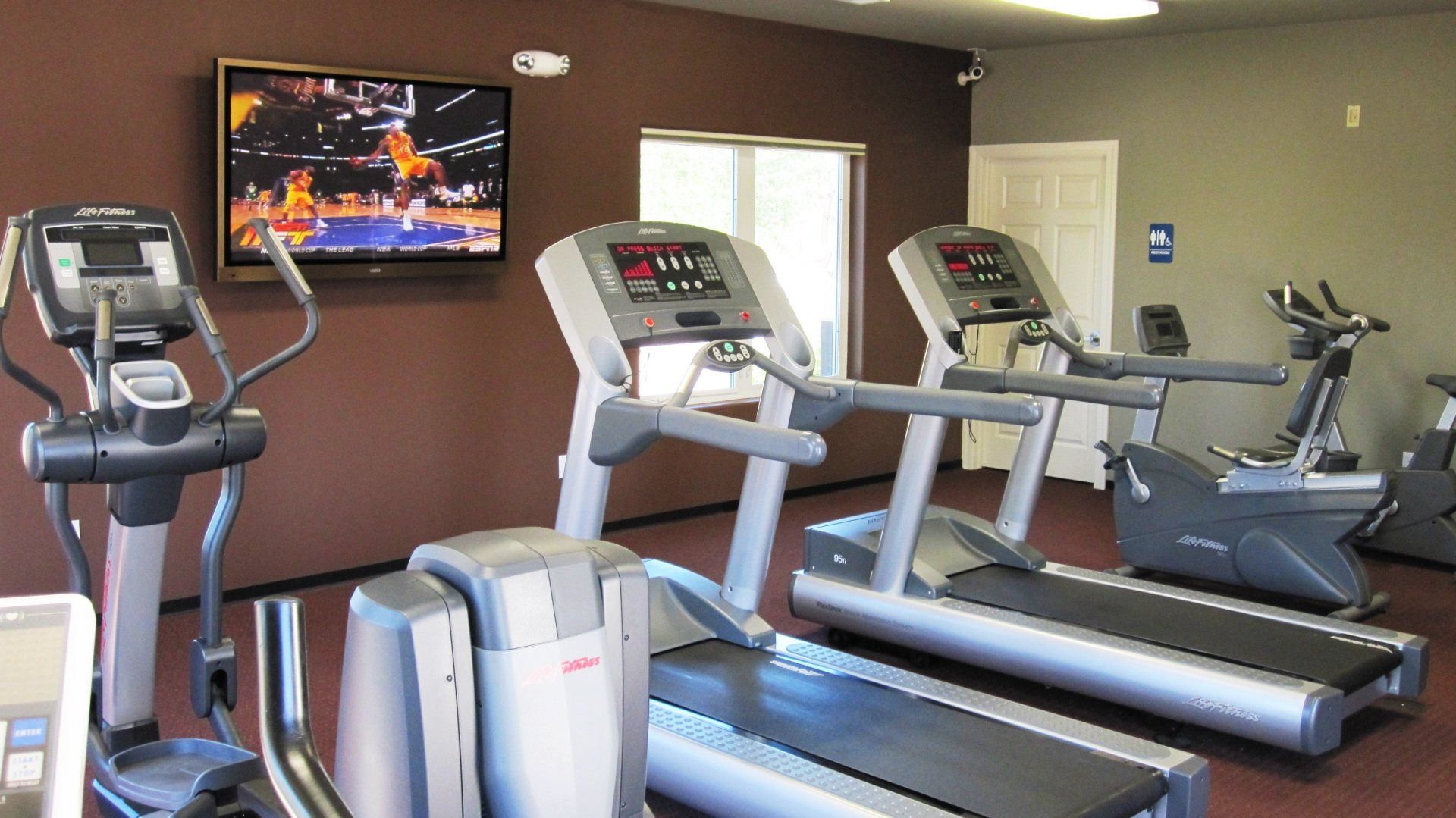 A gym with treadmills and a tv on the wall