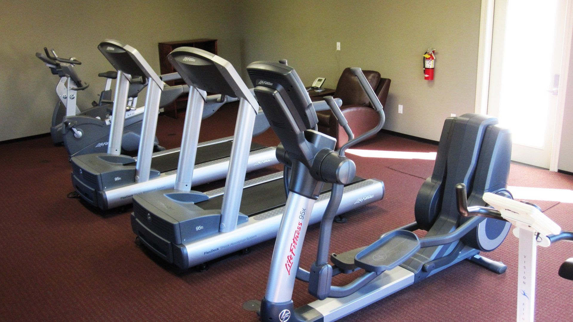 A row of treadmills and ellipticals in a gym