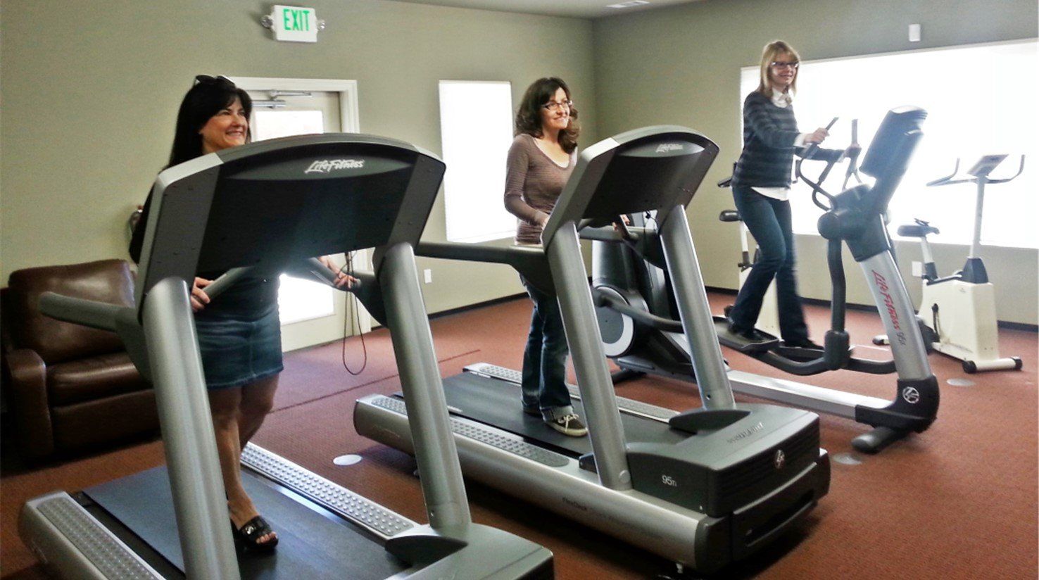 Three people are using treadmills in a gym