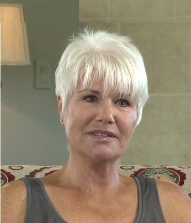 A woman with short white hair is sitting on a couch.