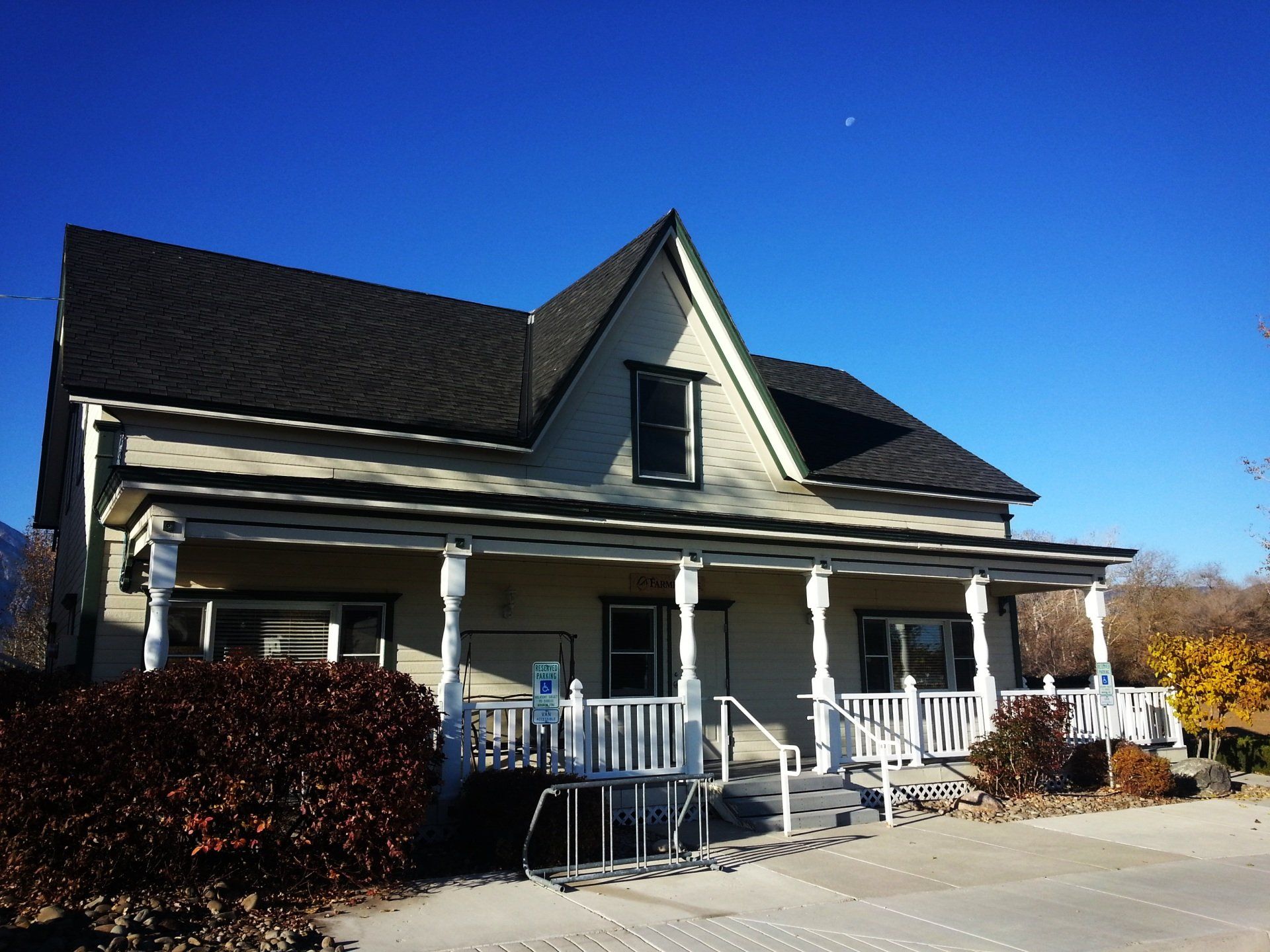 A white house with a black roof and a porch
