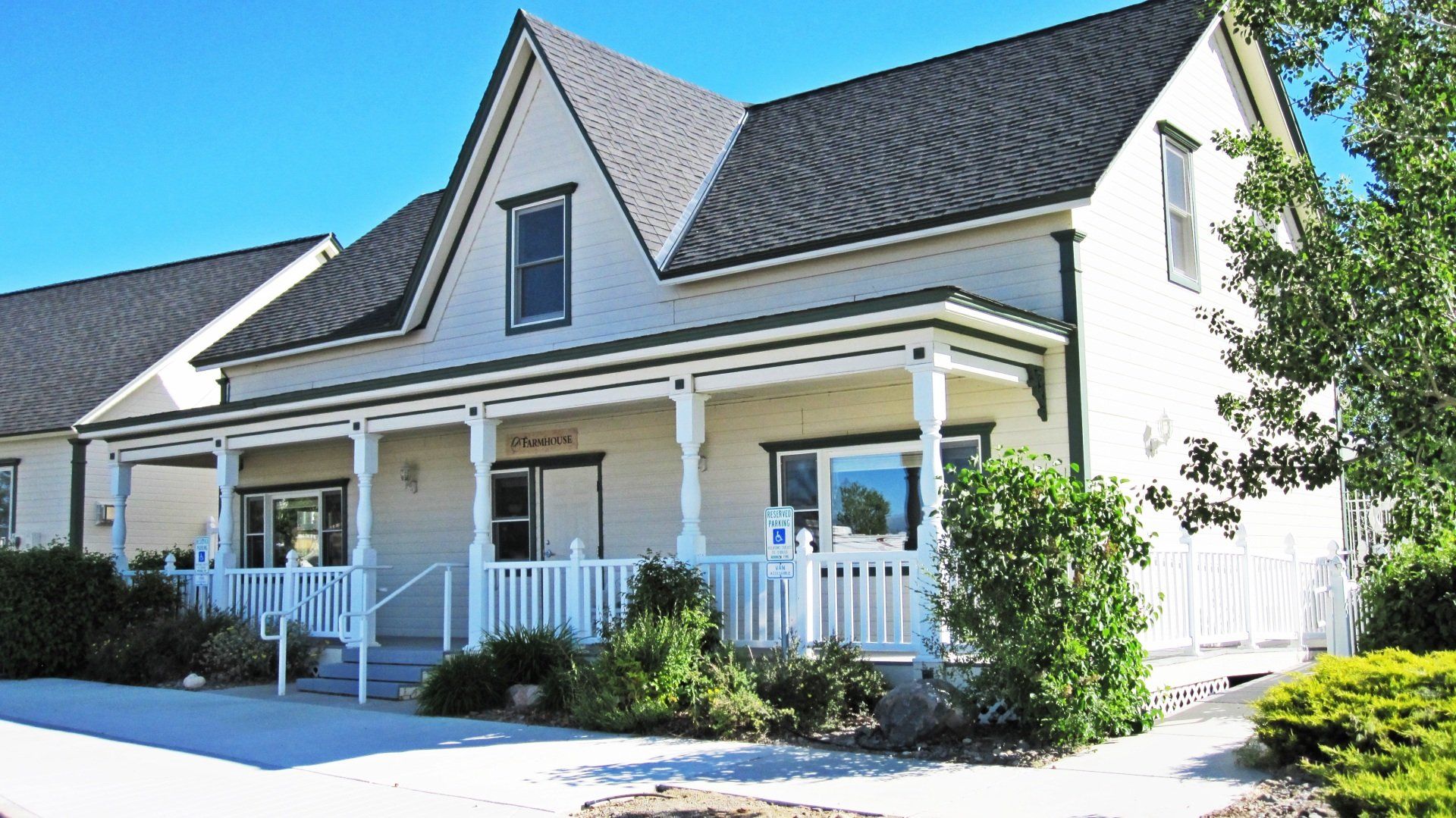 A white house with a black roof and a white porch