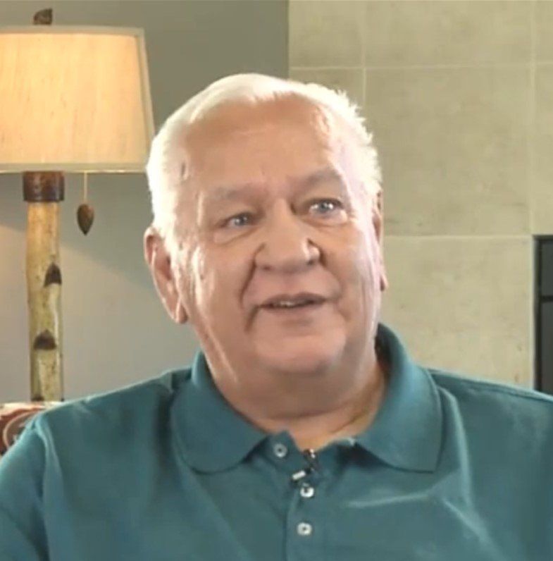 A man in a blue shirt is sitting in front of a lamp