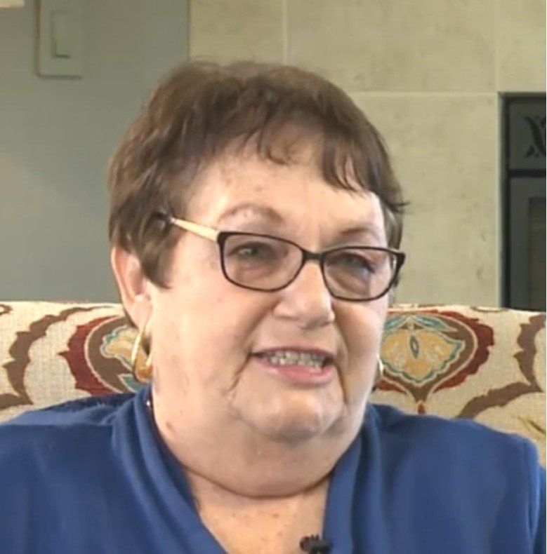 A woman wearing glasses and a blue shirt is sitting on a couch