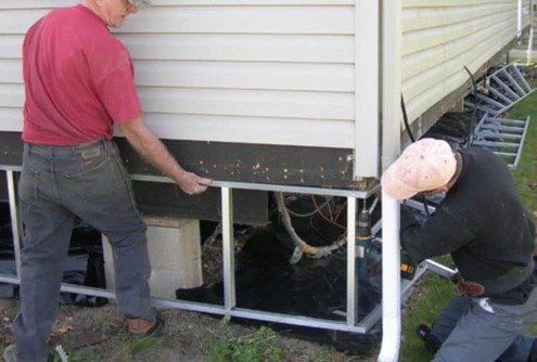 Two men are working on the side of a house