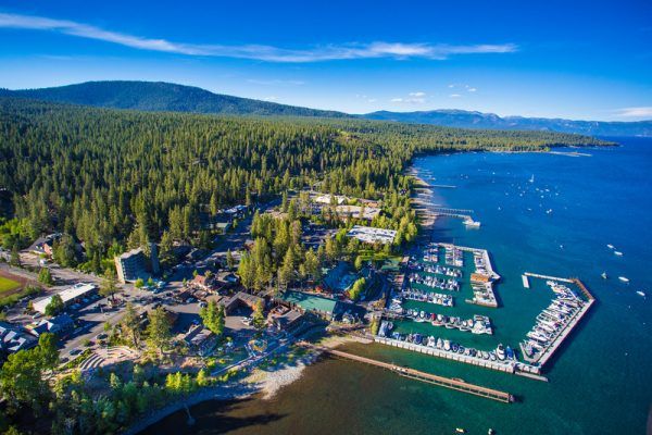 An aerial view of a marina surrounded by trees and mountains.