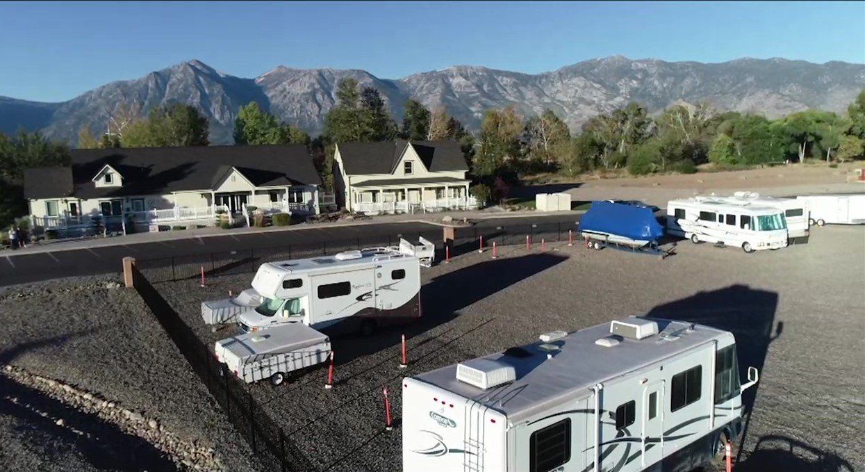 A group of rvs are parked in a lot with mountains in the background.