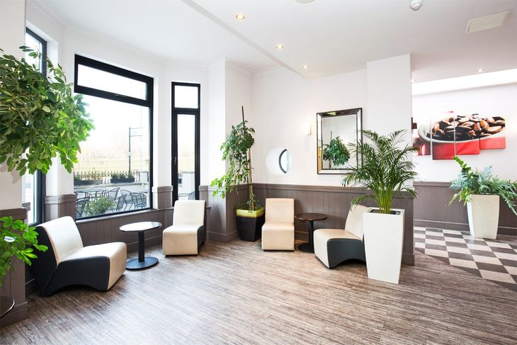Bright modern lobby with black and white chairs, potted plants, and large windows