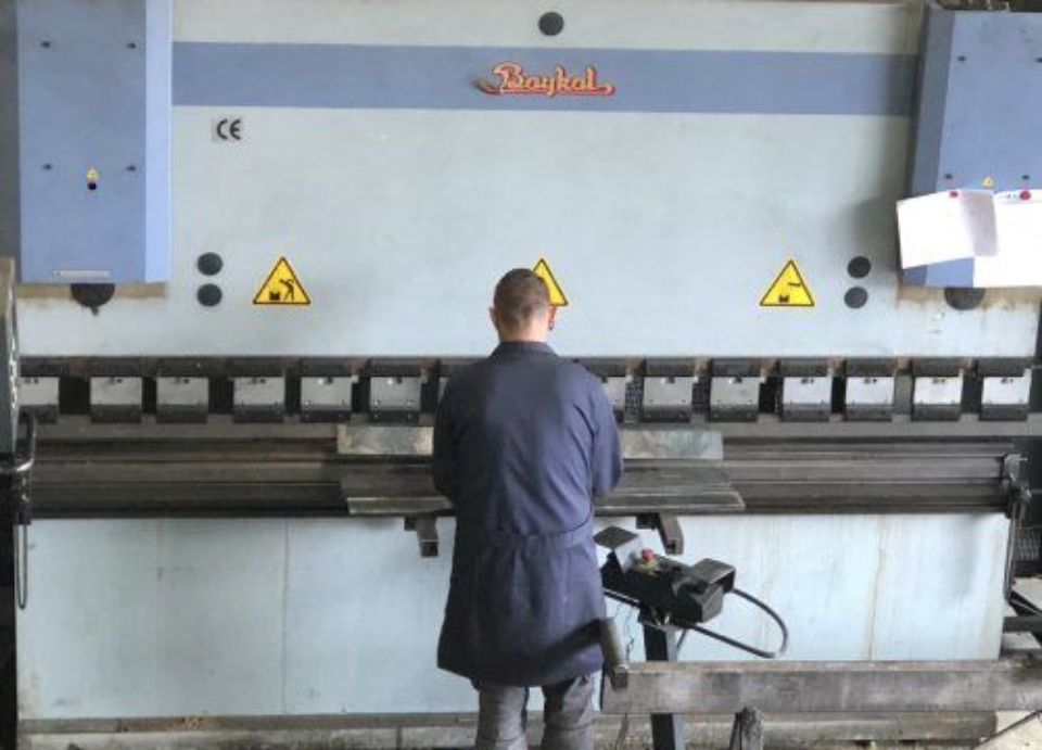 Operaio addetto alla pressa piegatrice industriale di grandi dimensioni in una fabbrica.