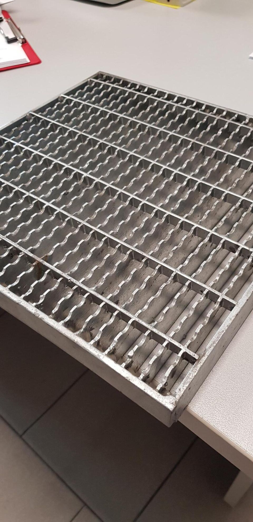 Vassoio portaoggetti in filo metallico su un piano di lavoro in un laboratorio o in una cucina.