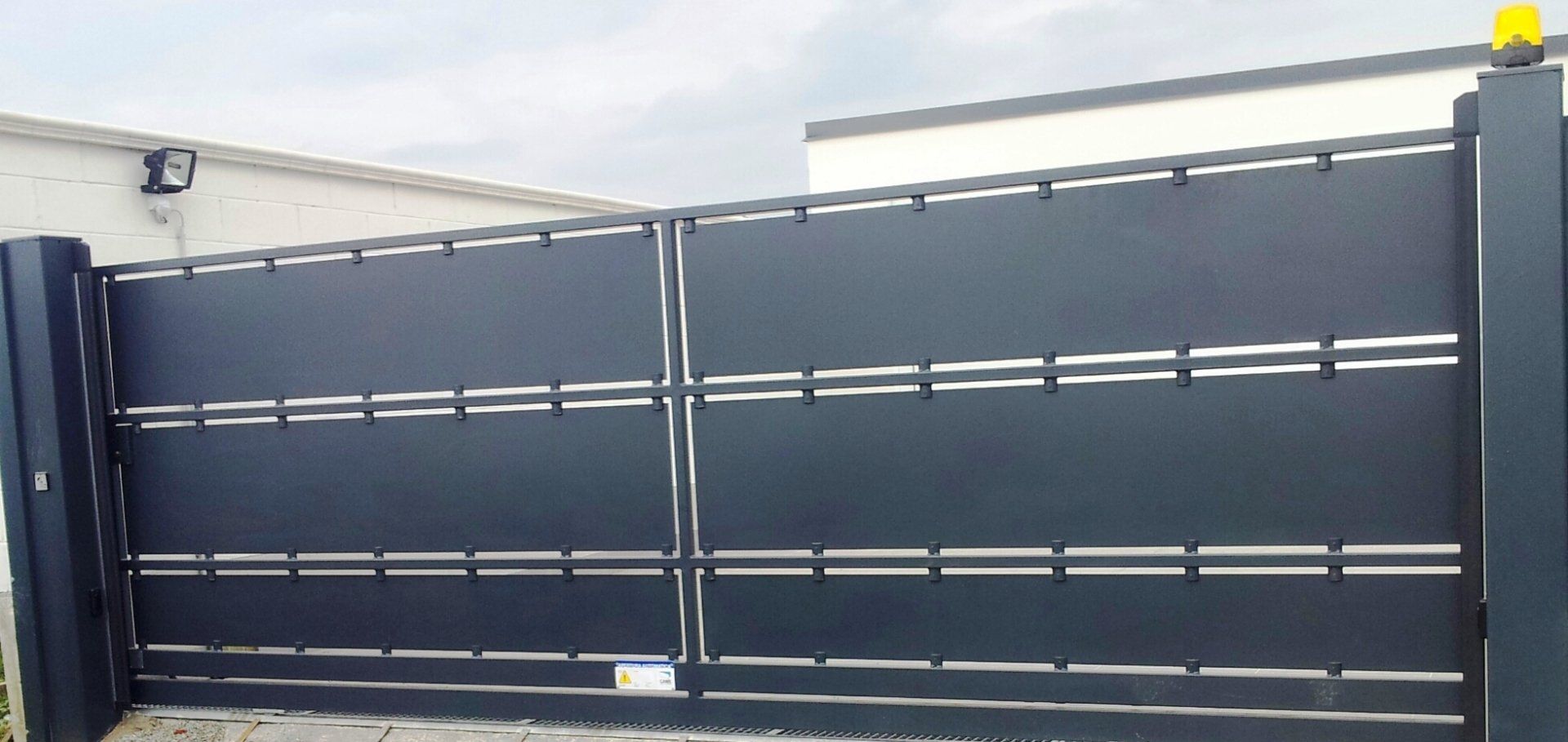 Cancello scorrevole in metallo nero con lamelle orizzontali all'esterno di un edificio