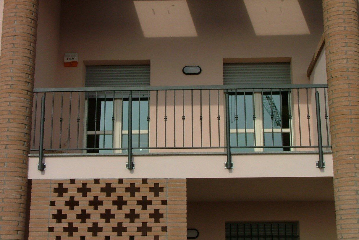 Balcone dell'appartamento con ringhiera verde, porte scorrevoli e muro in mattoni con intagli decorativi.