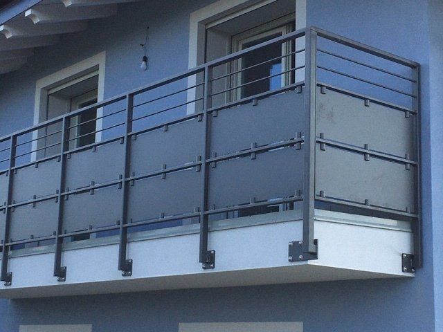 Balcone blu dell'appartamento con ringhiera in metallo e pannelli in vetro satinato
