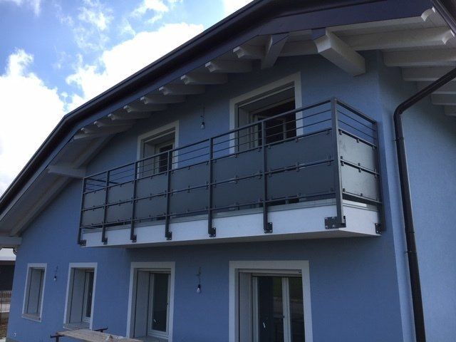 Casa blu con balcone e grandi finestre sotto un tetto spiovente