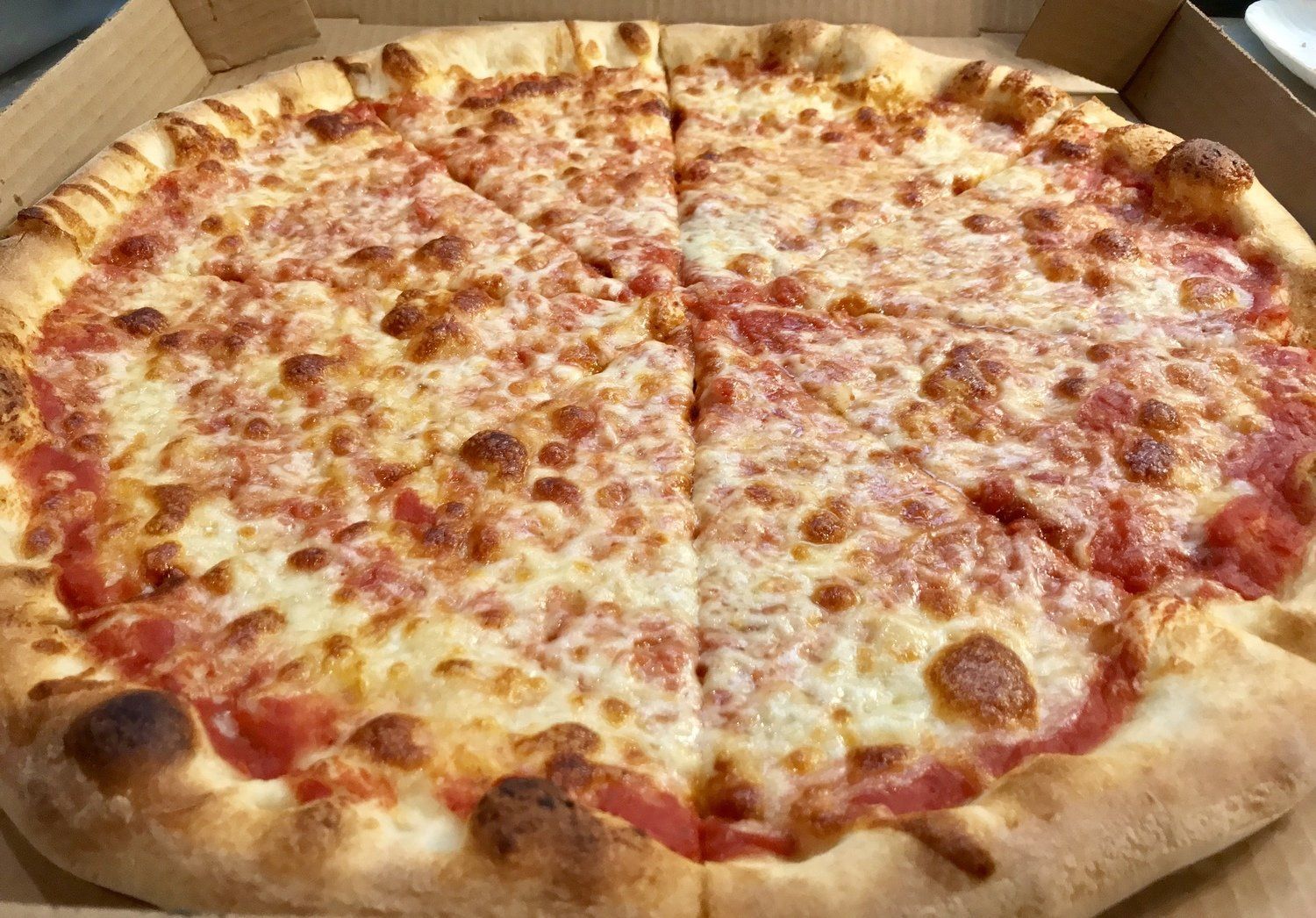 A large cheese pizza is sitting in a cardboard box.