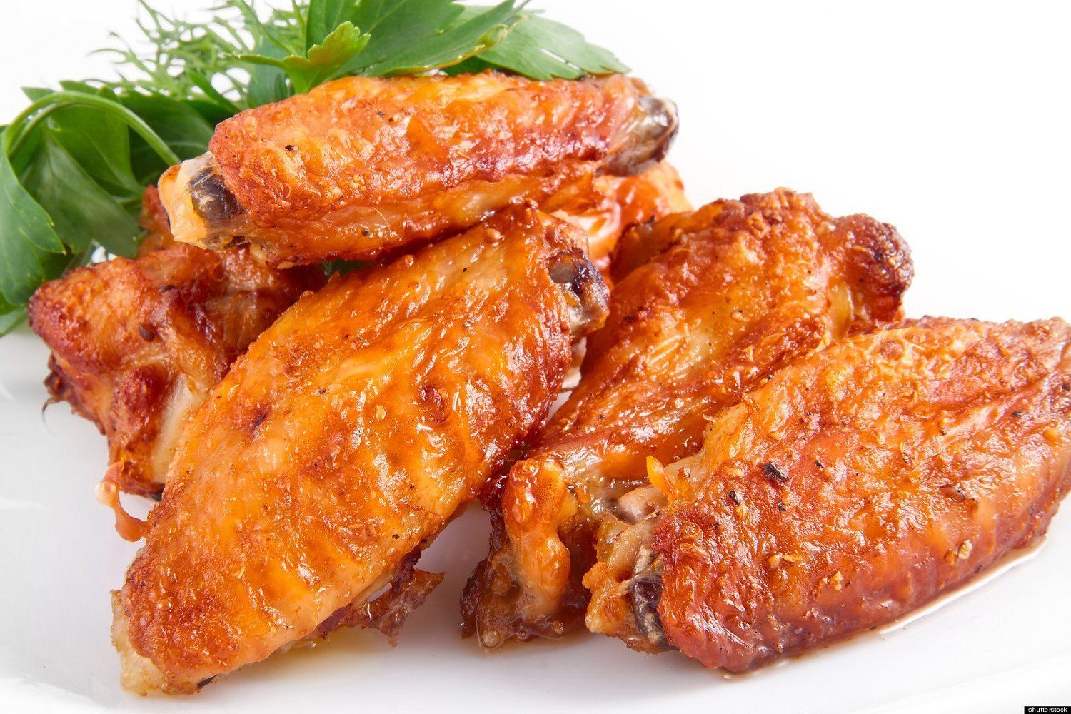 A white plate topped with chicken wings and greens.