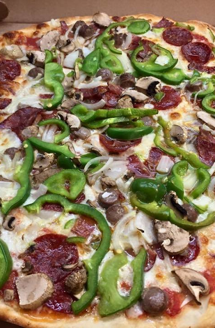 A pizza with pepperoni , mushrooms , onions and peppers on it is in a box.