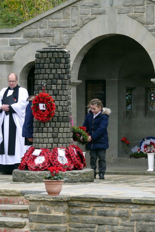 A boy is holding a wreath in front of a brick building.