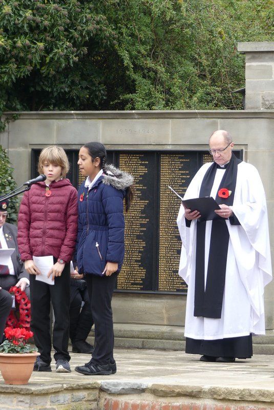 A man in a white robe is reading a book to a group of children.