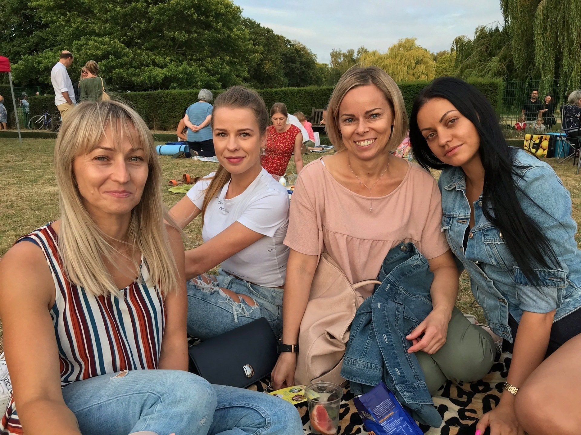 A group of women are sitting on a blanket in a park.