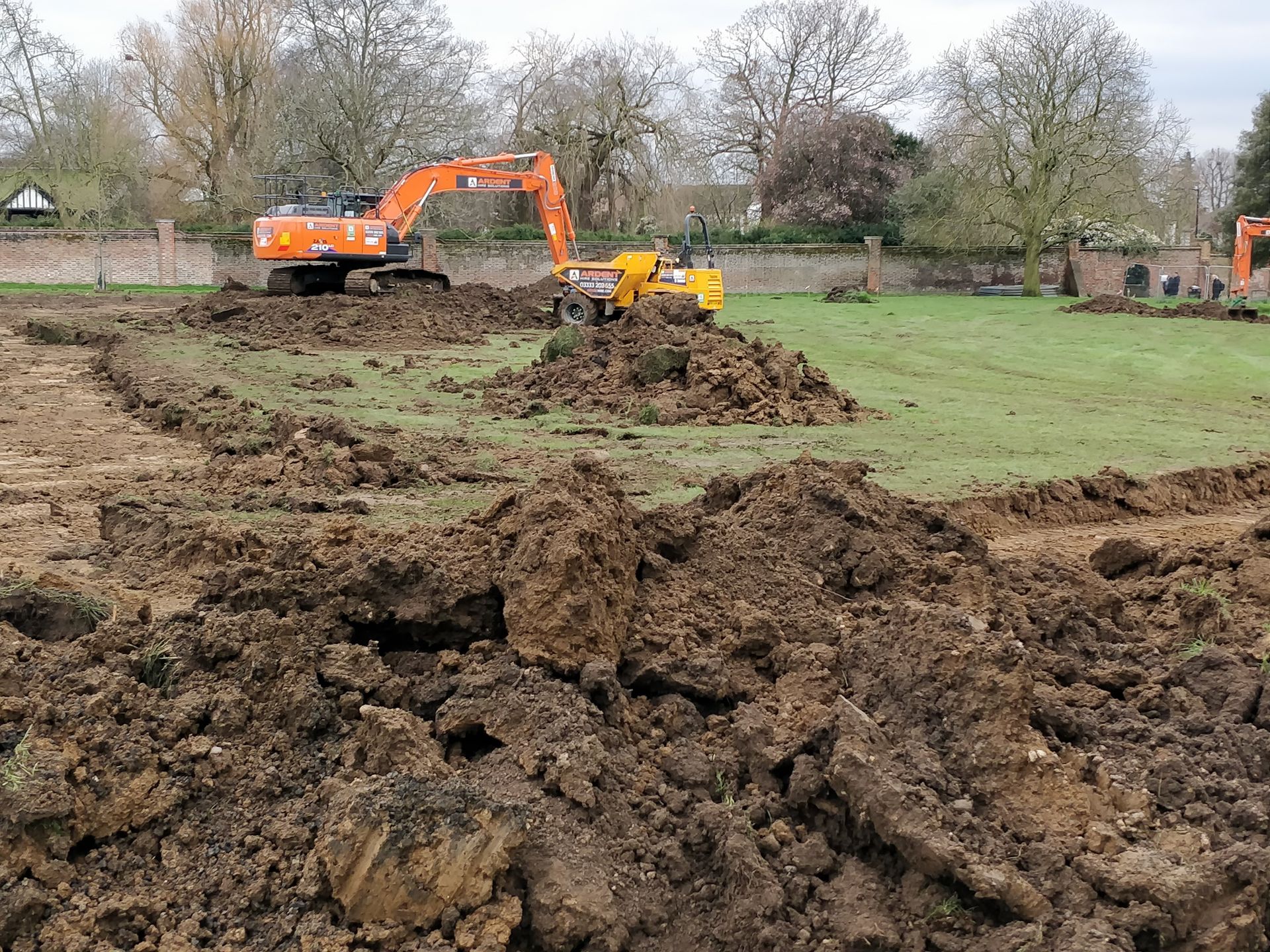 A large pile of earth is being excavated in a field.