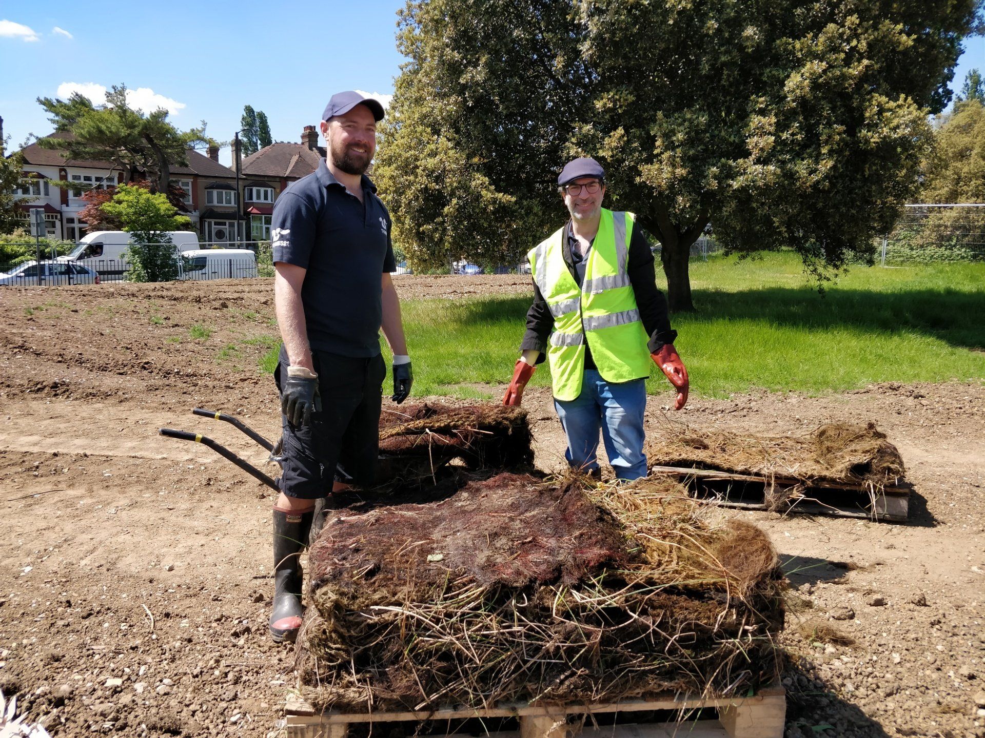 Two men are standing next to a pile of dirt on a pallet.