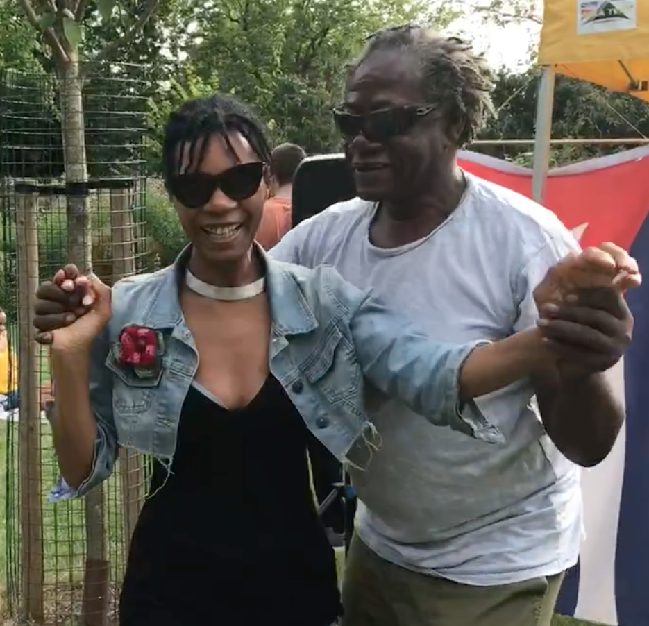 A man and a woman are dancing in front of a cuban flag