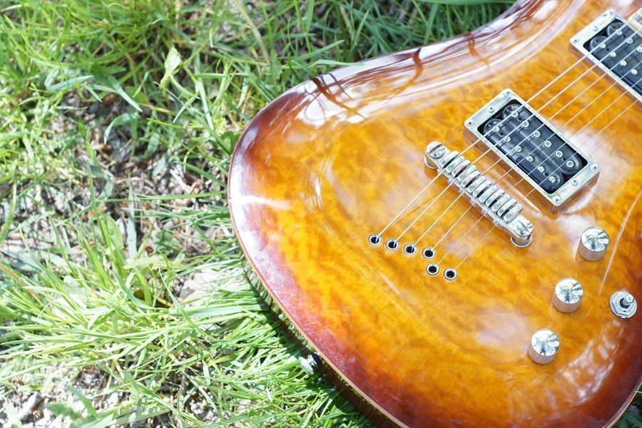 An electric guitar is laying in the grass.