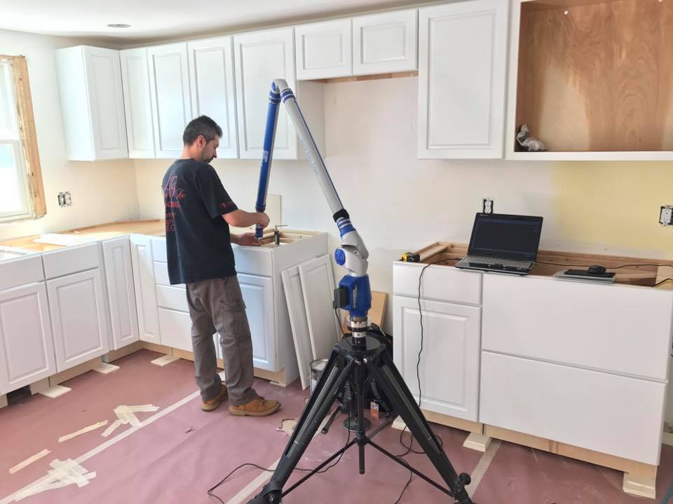 Worker installing cabinets in a bright kitchen with a ladder and tools on the counter
