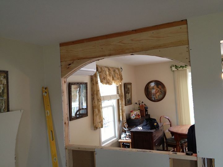 Interior view of a home with a wooden archway, window, and dining table in a beige room