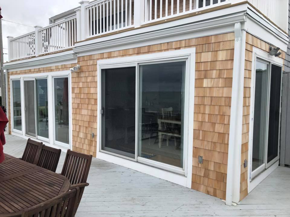 Modern house exterior with sliding glass doors and white trim on a wooden deck.