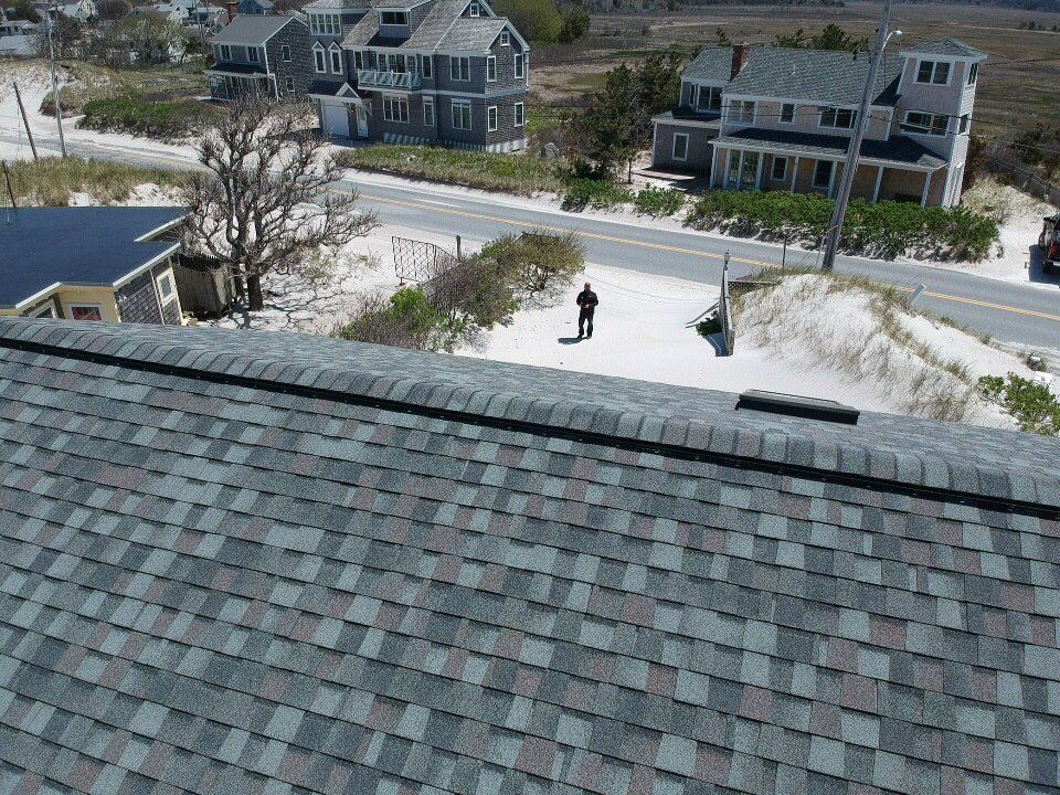 Person standing on a sandy path near beach houses, viewed from a rooftop.