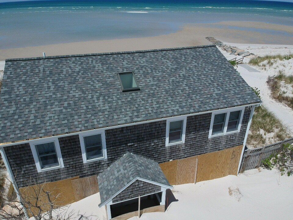 Aerial view of a house on a sandy beach with ocean in the background