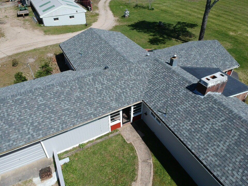 Aerial view of a gray-roofed building with a central courtyard and nearby outbuildings.