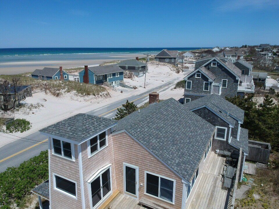 Coastal neighborhood with beach houses and a road beside the ocean on a sunny day