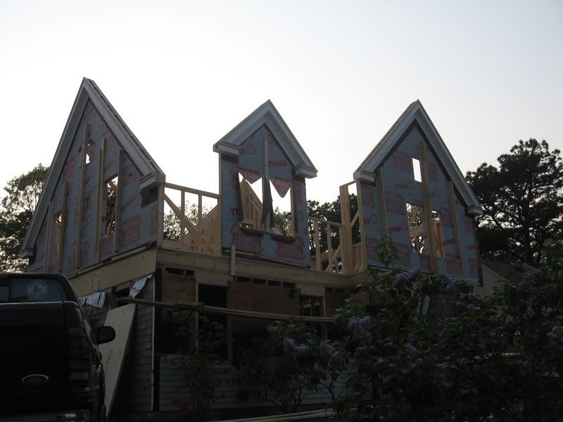 Modern house with three steep triangular roof sections and a wooden deck at dusk