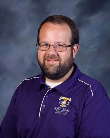 Man with glasses and beard, wearing a purple polo shirt with 