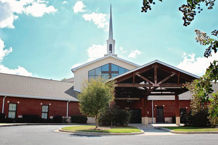 Brick church with steeple, covered entrance, and blue sky.