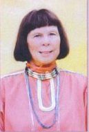 Portrait of a woman in a pink traditional outfit with a black bob haircut and beaded necklace