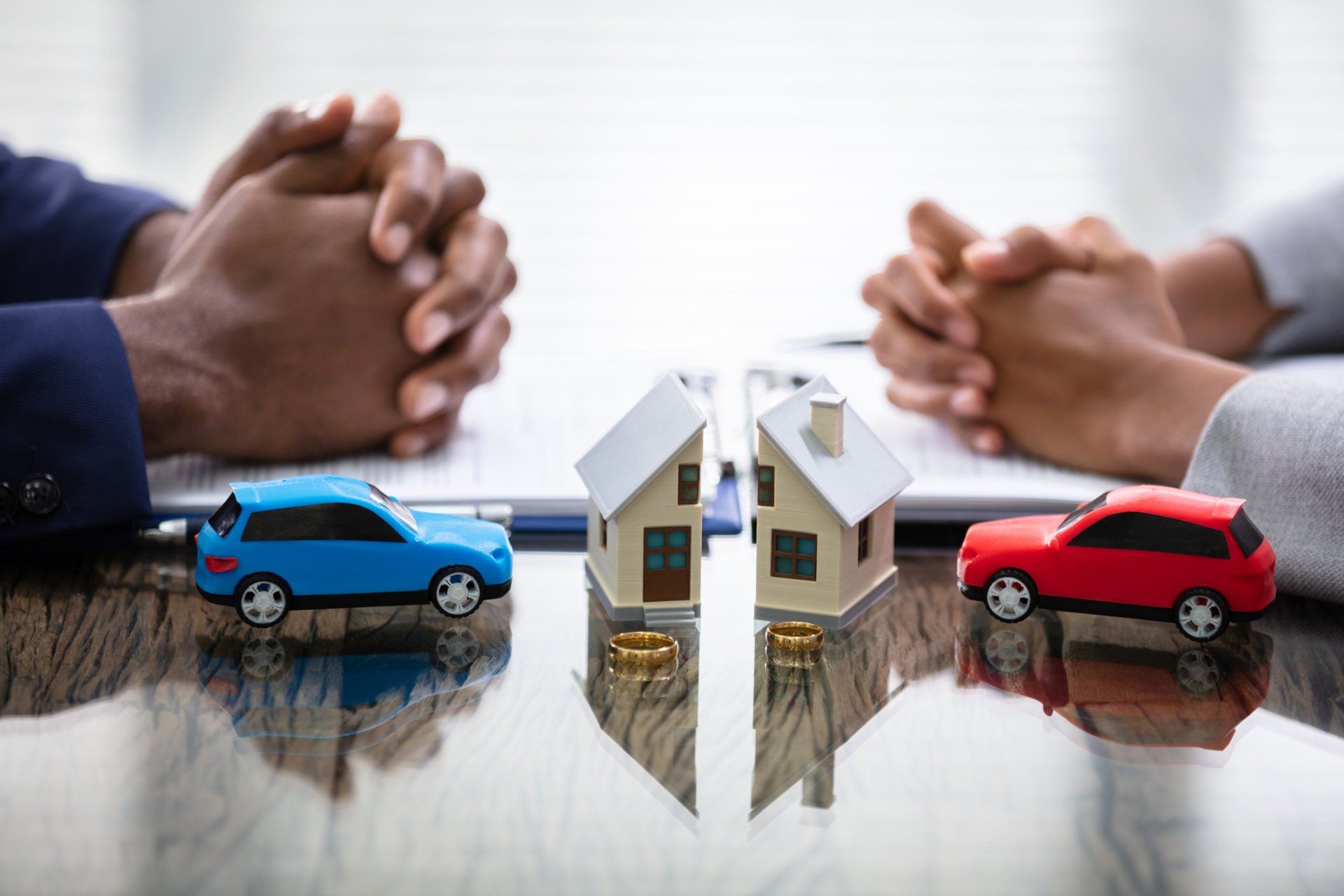 A man and a woman are sitting at a table with toy cars and houses.
