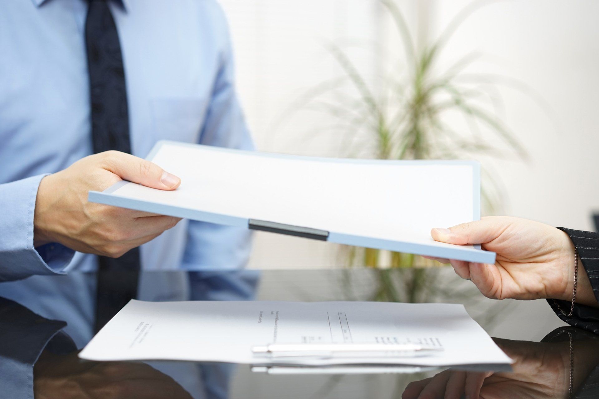 A man is handing a piece of paper to another man.