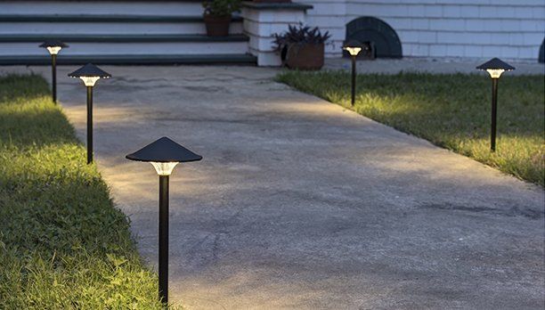 A row of lights on a sidewalk in front of a house.