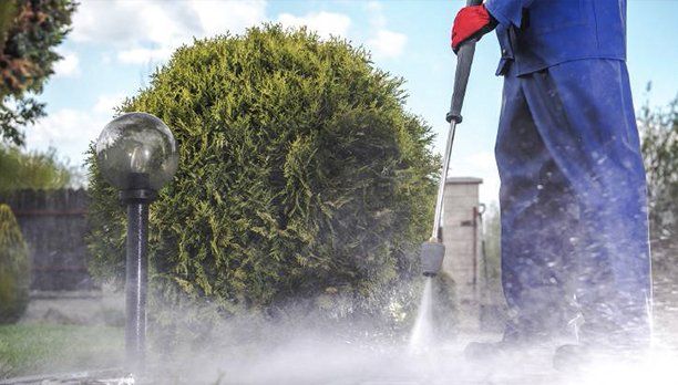 A man is using a high pressure washer to clean a sidewalk.