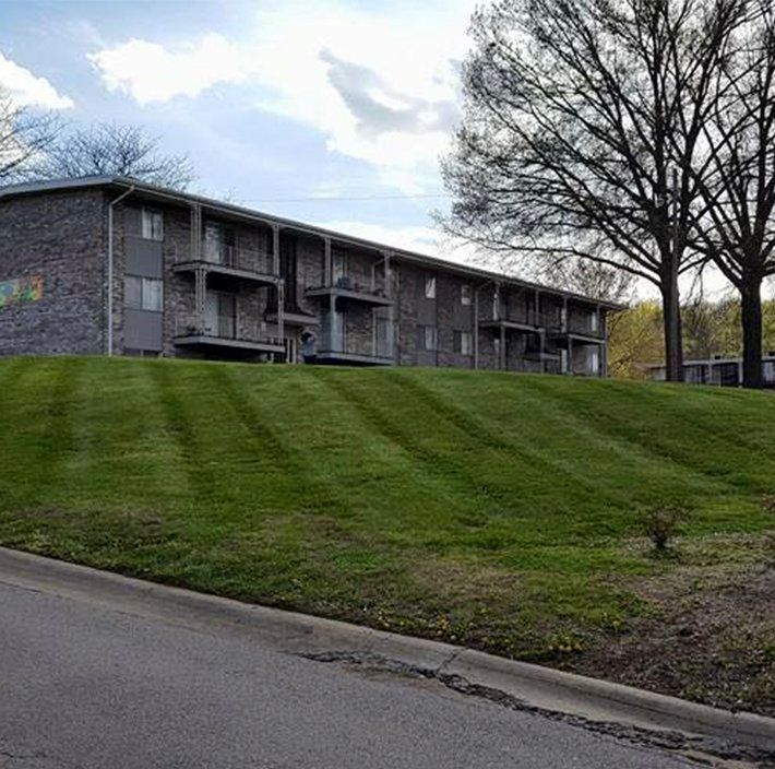 A large apartment building with a lush green lawn in front of it.