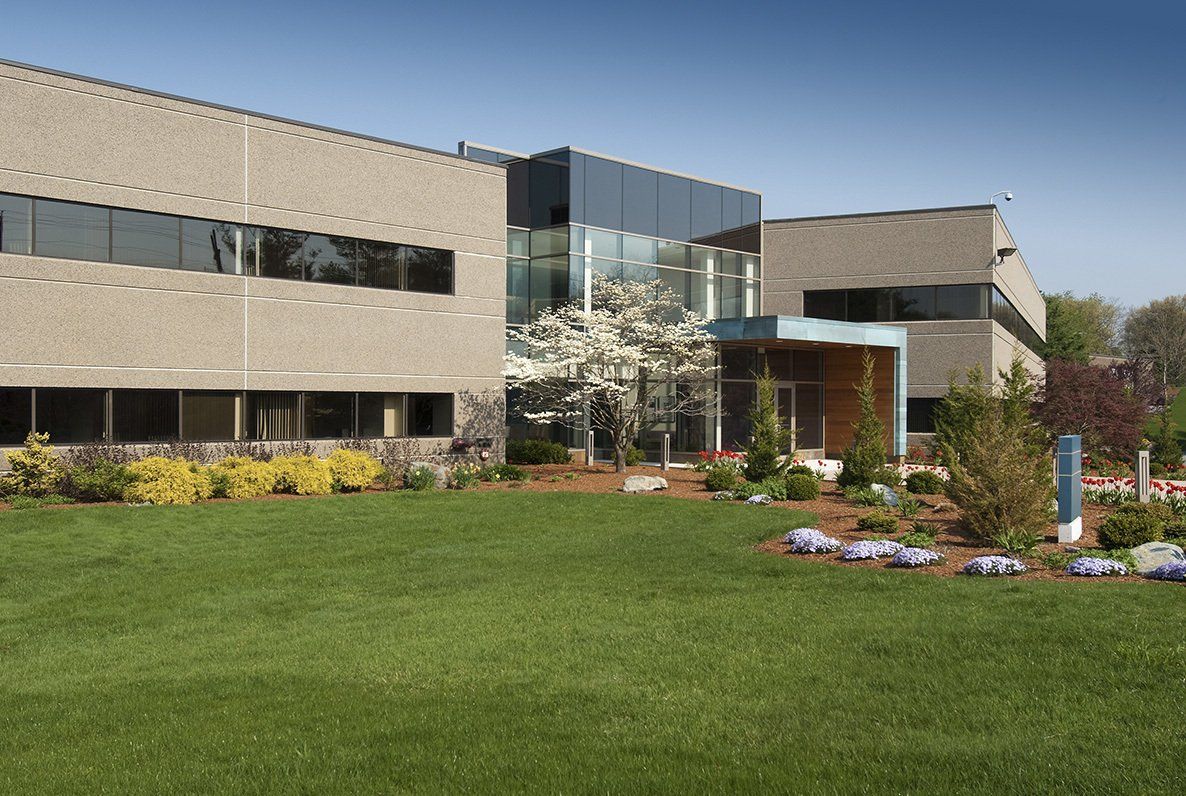 Modern building with a gray facade, glass entrance, and manicured lawn under a blue sky.